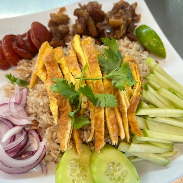 Proud Thai's fried rice with sliced omelet, Chinese sausage, sweet pork, red onion, cucumber, and lime.