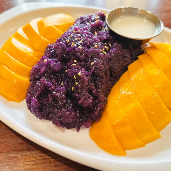 Proud Thai's purple sticky rice with mango slices and a side of coconut milk.