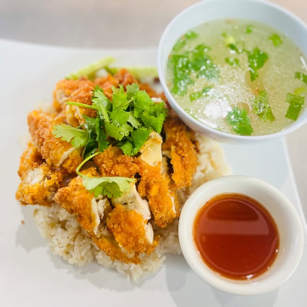 Crispy fried chicken over rice, garnished with cilantro, served with clear soup and chili sauce.