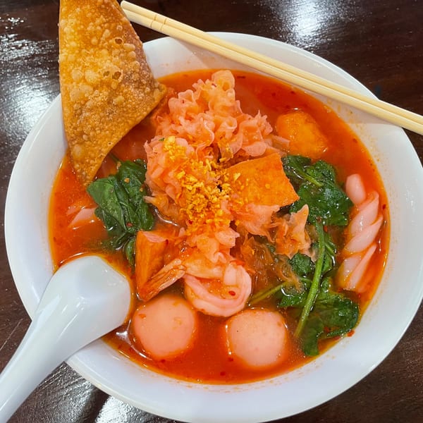 Proud Thai's vibrant red Yen Ta Fo noodle soup with shrimp, fish balls, and crispy wonton.