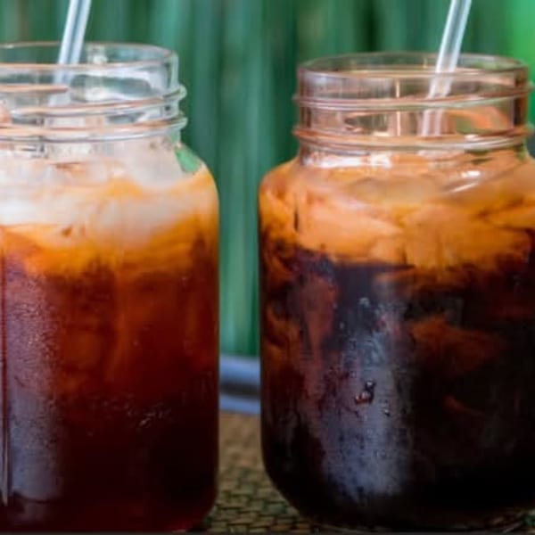 Two mason jars of iced Thai tea with straws, one lighter and one darker.